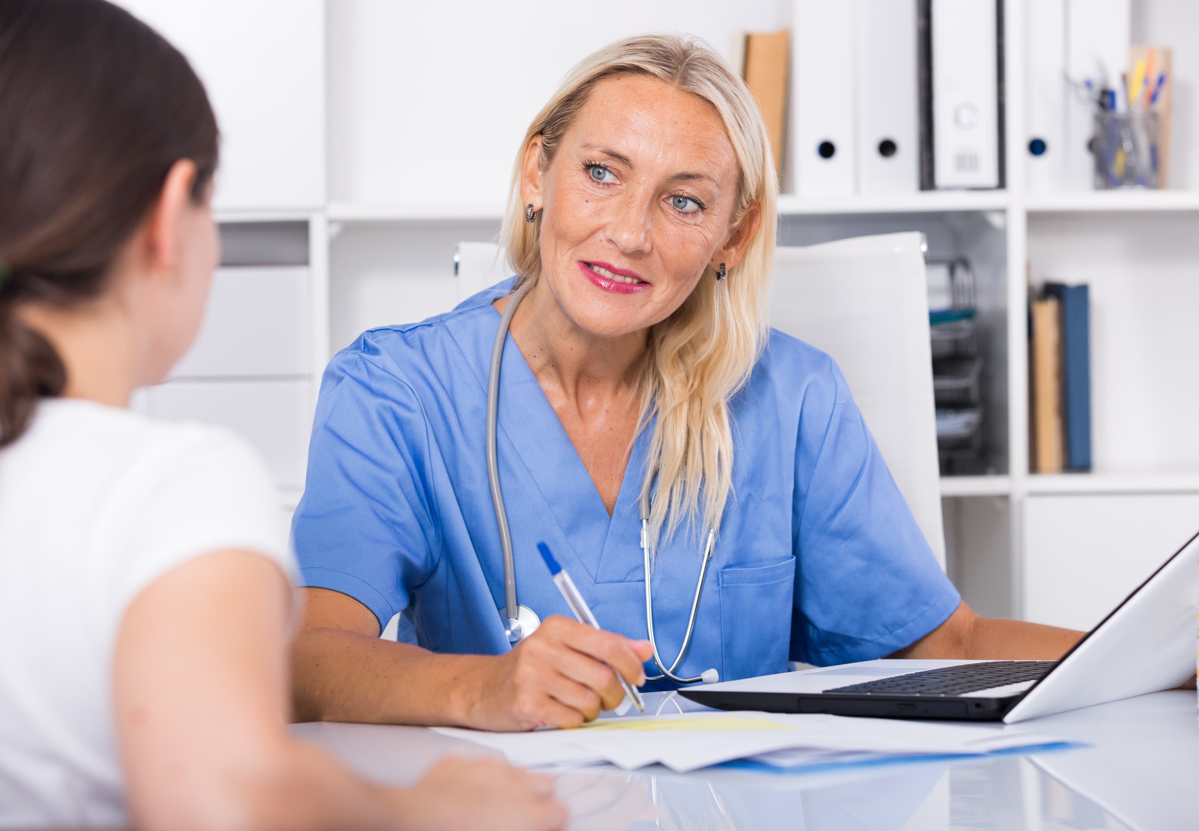 Female doctor listening attentively to a patient during a consultation — calm, supportive clinical conversation.